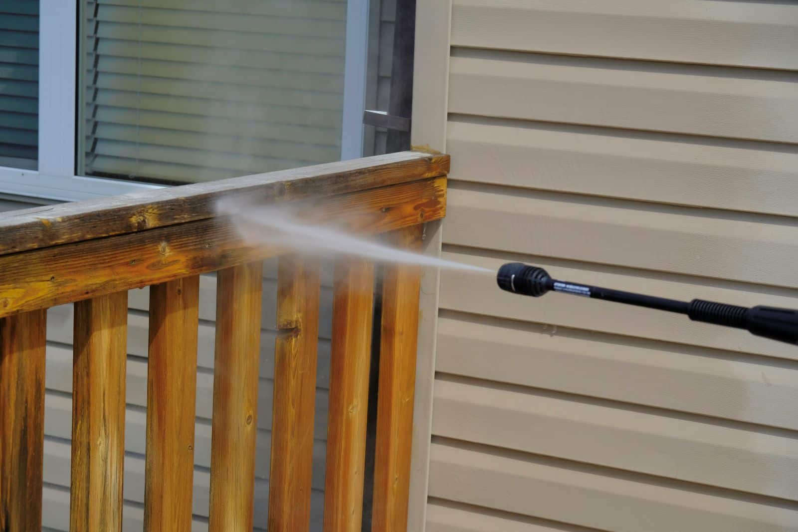 person cleaning wooden railing on deck