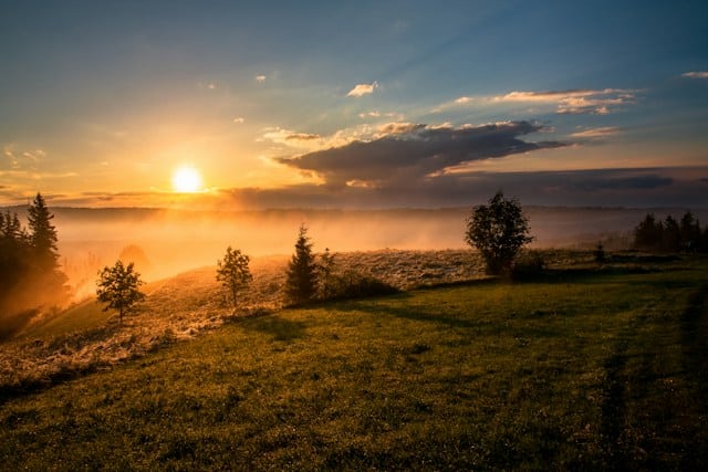 The sun rising in the morning over a foggy valley