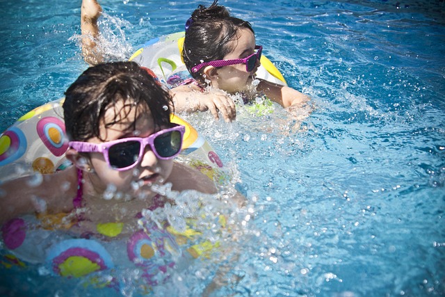 two young girls swimming in a pool wearing pink sunglasses and tubes