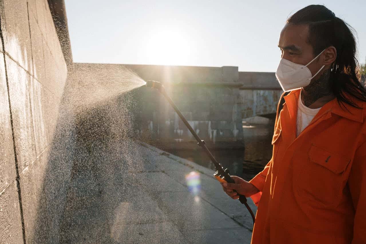 man in orange jumpsuit and mask washes wall