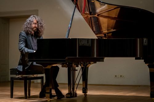 A man is playing and practicing piano to improve his skill.