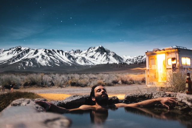 A man relaxing in a cold pool, with a mountain in the background