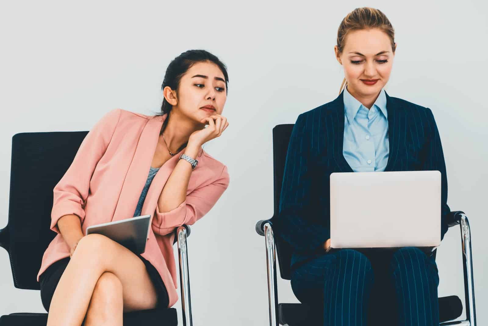 A woman spies on another woman's laptop.